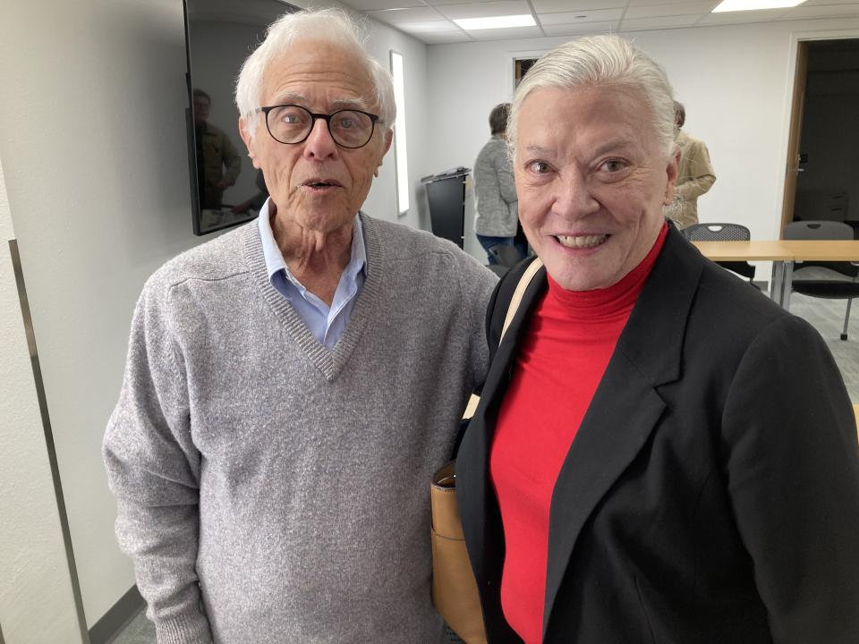 Norman Sherman poses with a woman in a blazer and red shirt that attended his talk