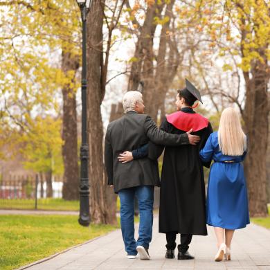 Parents walking down path with child college graduate.