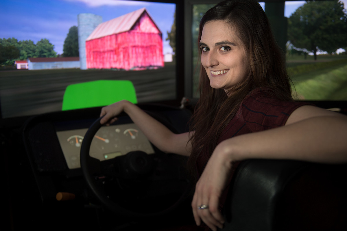 Kayla Faust sits inside a farm tractor simulator