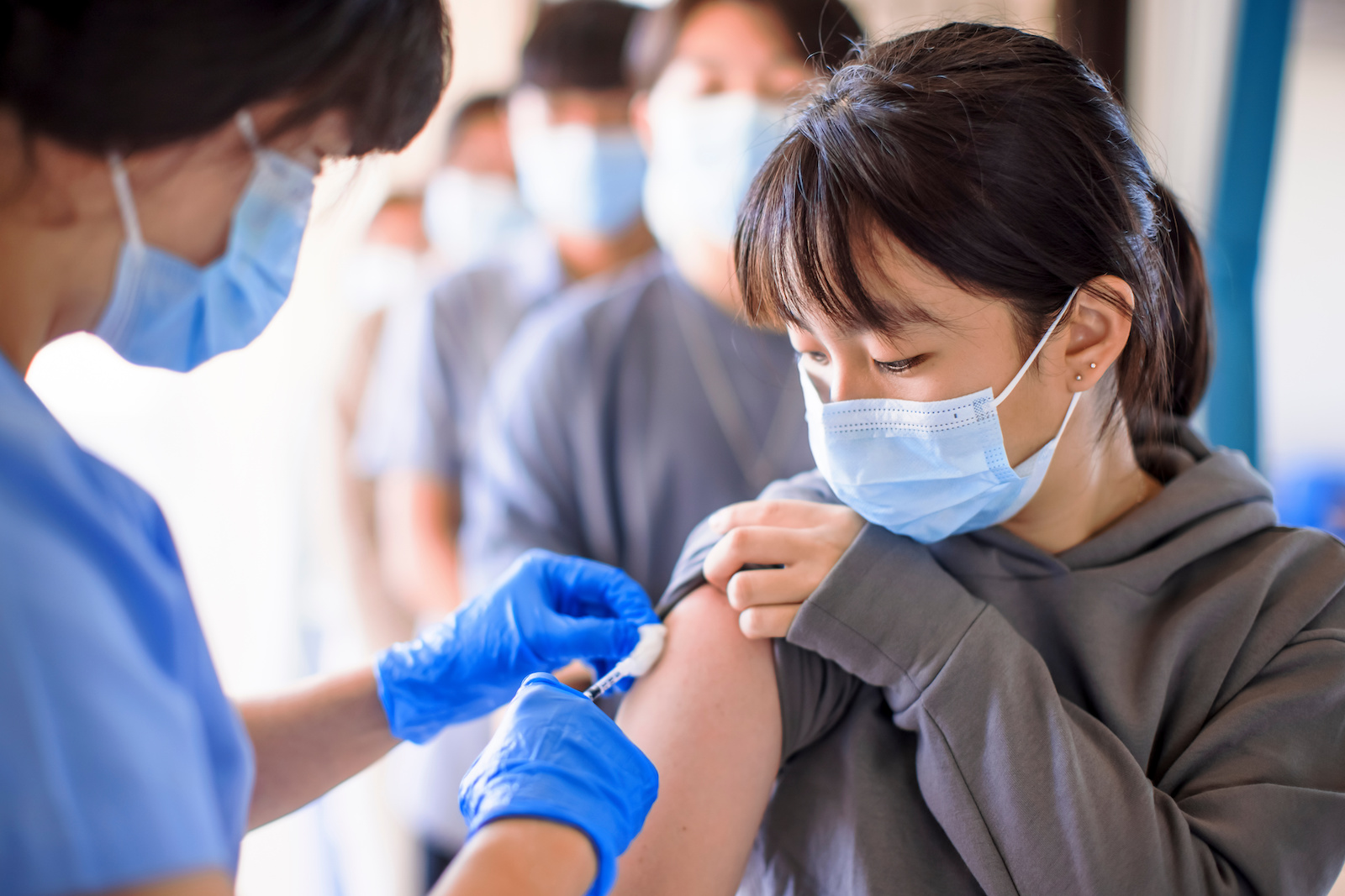 A person holds up their sleeve to receive a vaccination shot