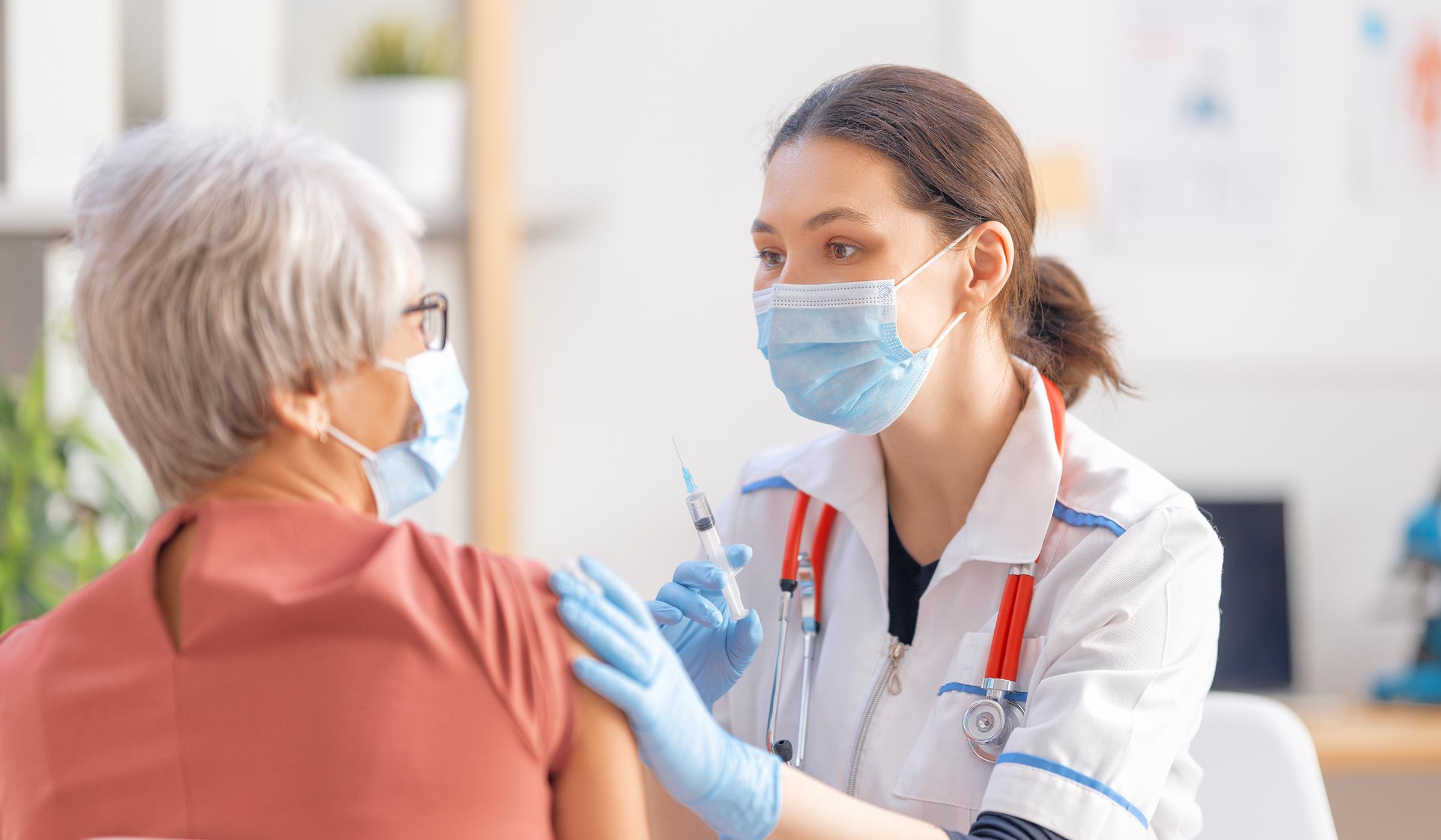 Nurse giving older woman a vaccination