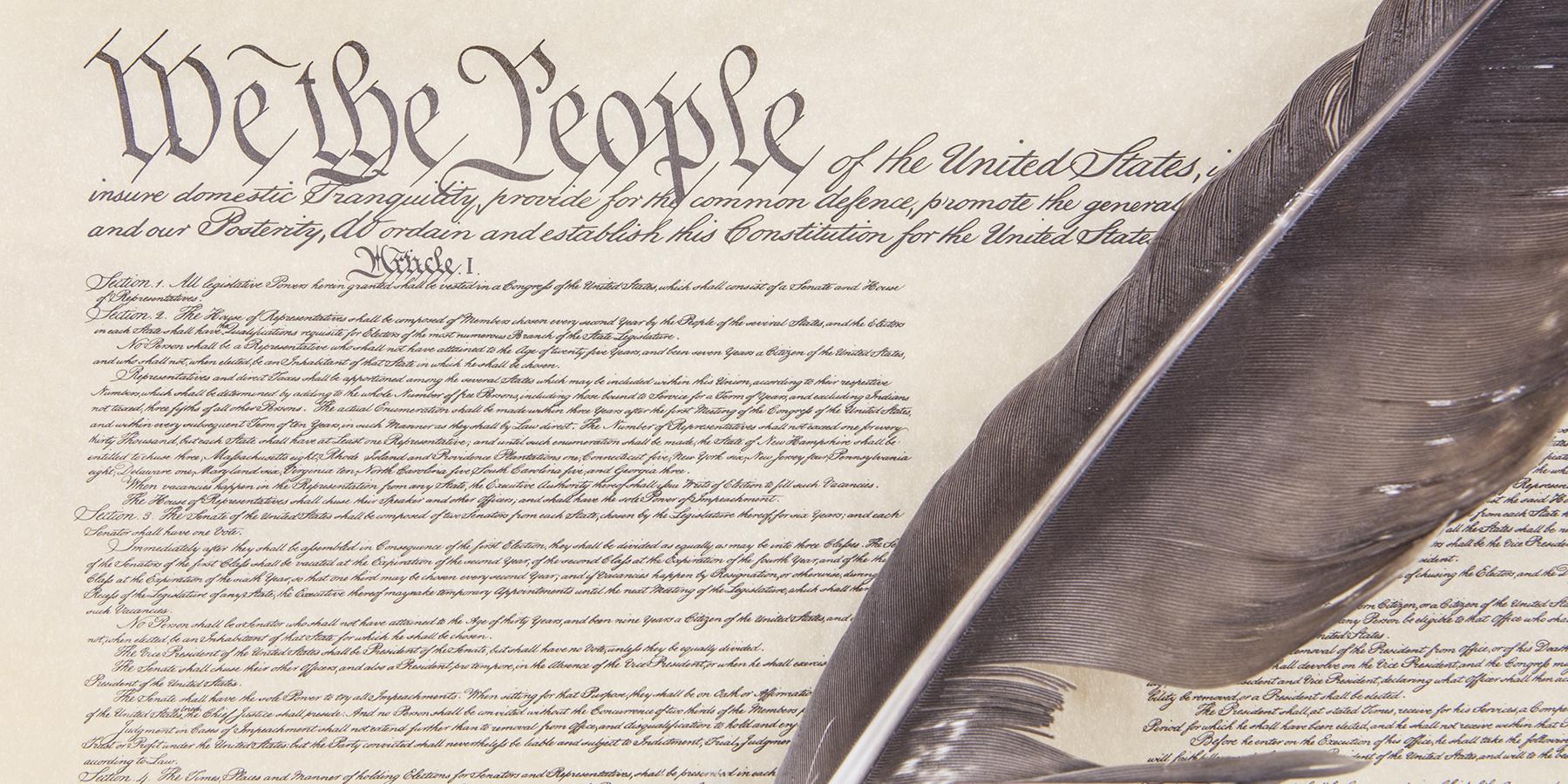 Sketch of the US Constitution's preamble and first article, with a feather quill laying over the document