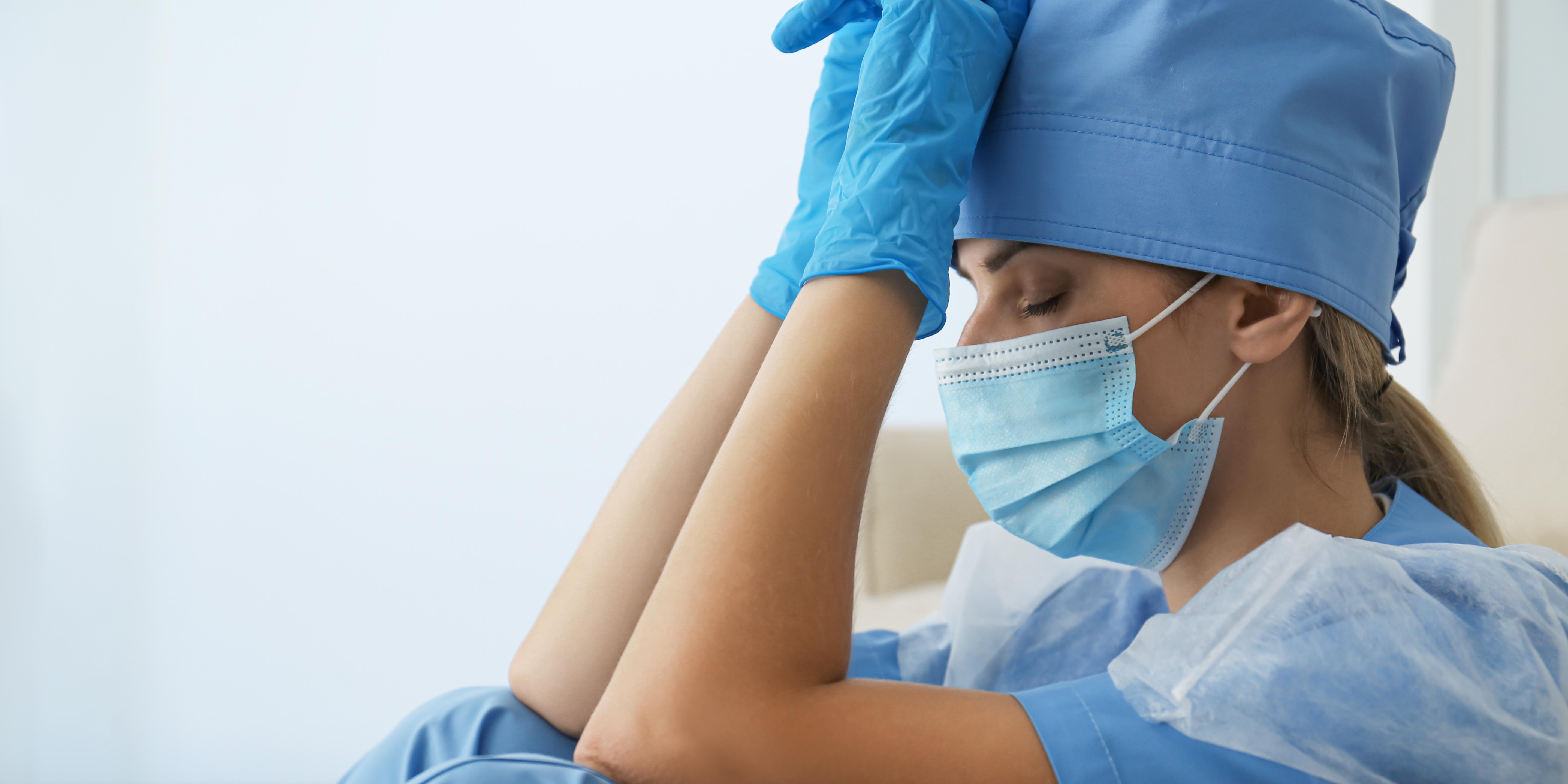 a woman in medical PPE looking physically exhausted