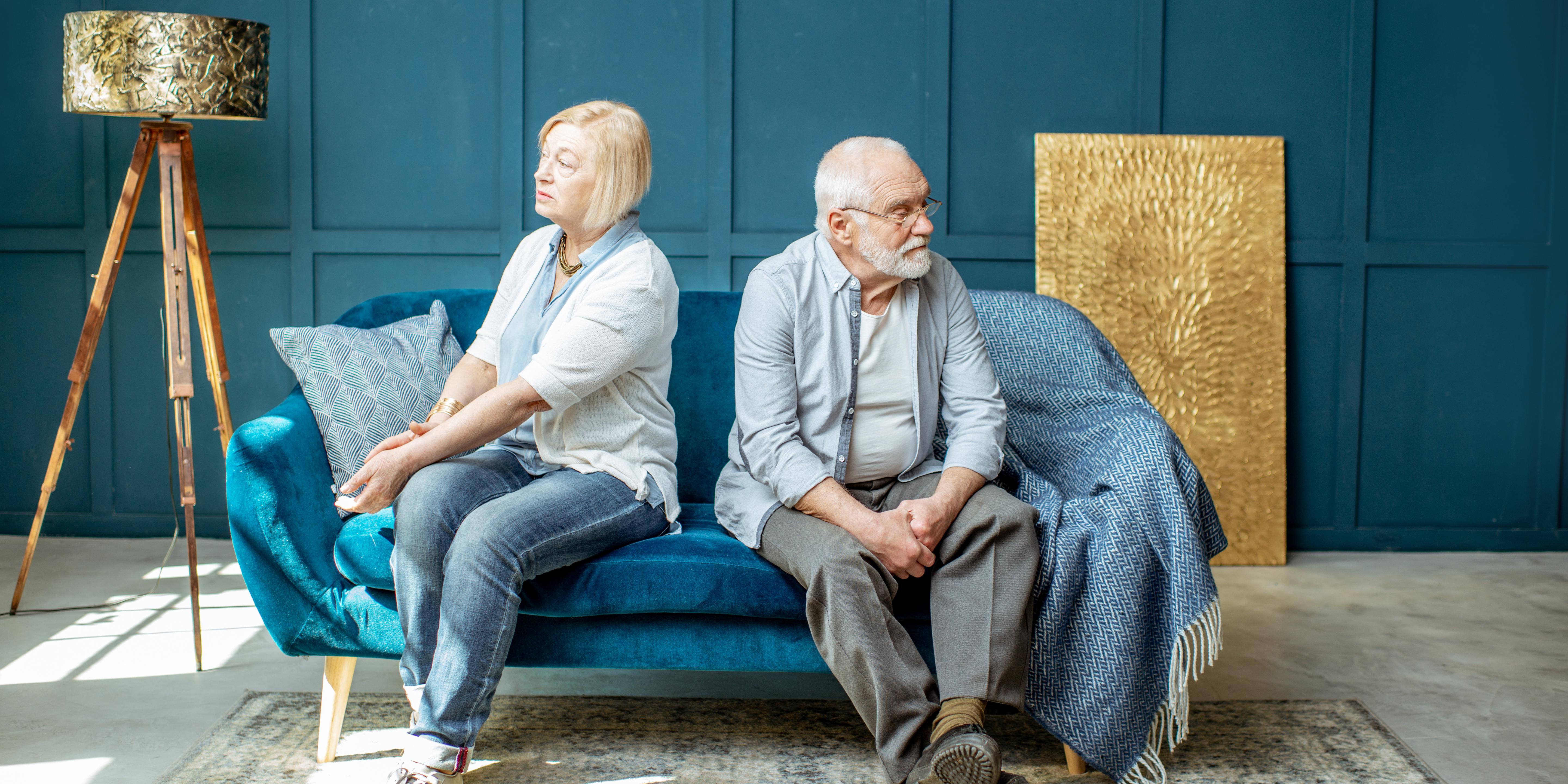 an older couple sitting on a couch facing away from each other - presumably going through a divorce