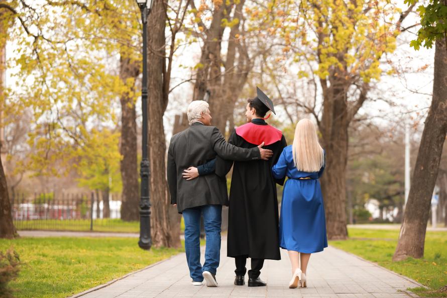 Parents walking down path with child college graduate.
