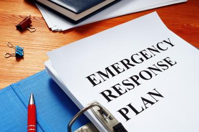 Binder on a desk, open to a title page that says Emergency Response Plan