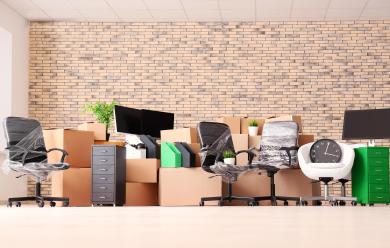 a cluttered office with boxes, chairs, and computers packed up