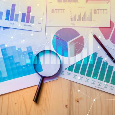 magnifying glass laying on documents with graphs and analytics data