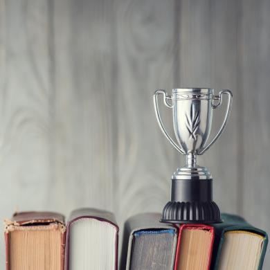 a silver cup-style trophy sitting on the spines of five books 