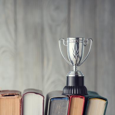 a silver cup-style trophy sitting on the spines of five books 
