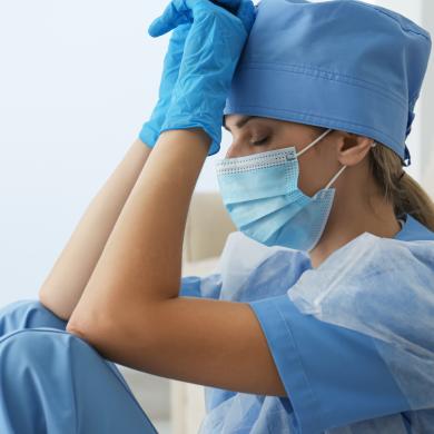 a woman in medical PPE looking physically exhausted